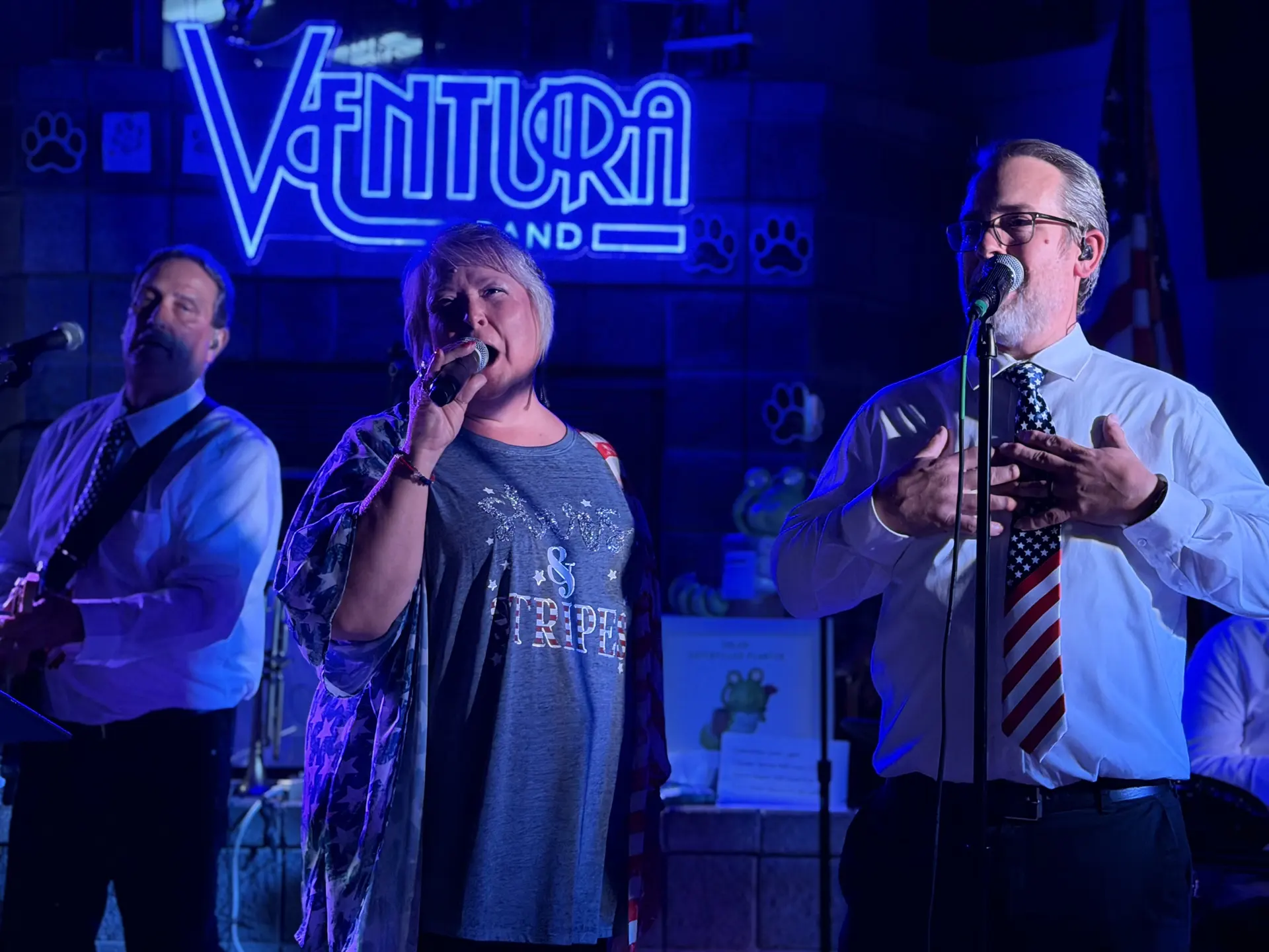 Ventura Band singer performing in front of the lit Ventura Band sign, with a keyboardist beside her